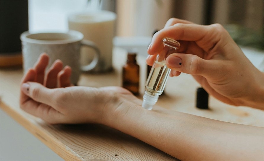 En person dupper en flaske med olie mod sin underarm. En person dupper en flaske med olie mod sin underarm.