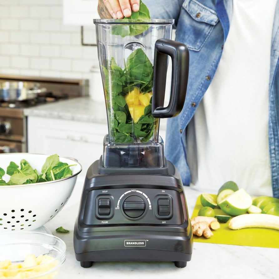 Blender med en smoothie af spinat og frugter.