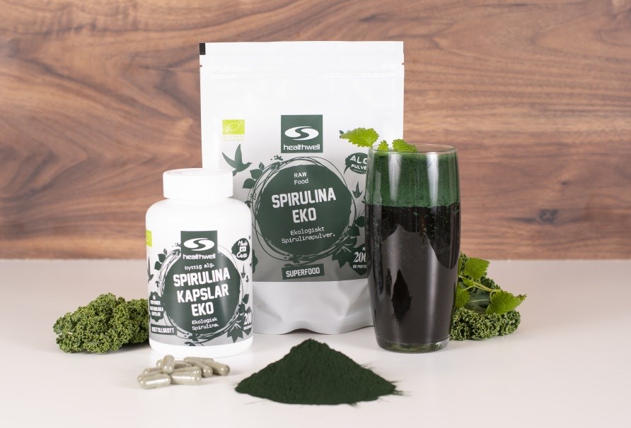 Healthwell Spirulina Pulver og Spirulinakapsler samt en grn spirulina-smoothie.