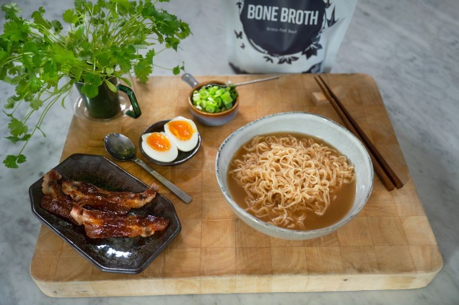 En sk�l med f�rdig bone broth ramen st�r omringet af ingredienserne.