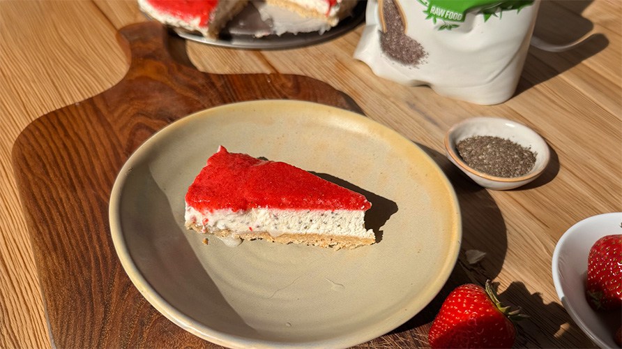Et stykke chia-cheesecake med jordb�r p� en tallerken, som st�r p� en tr�bakke sammen med en lille sk�l chiafr�.