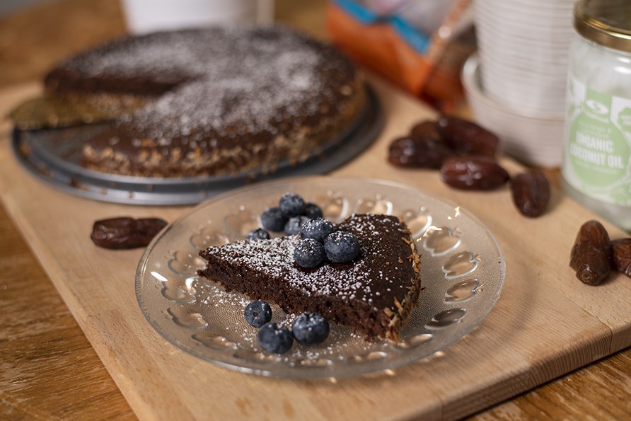 Chokoladekage med dadler på en tallerken toppet med friske blåbær. 