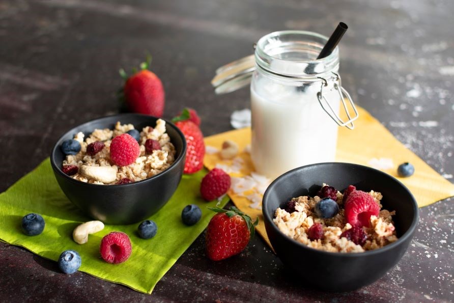 L�kker anretning af yoghurt med granola og friske b�r samt en glasflaske med m�lk.