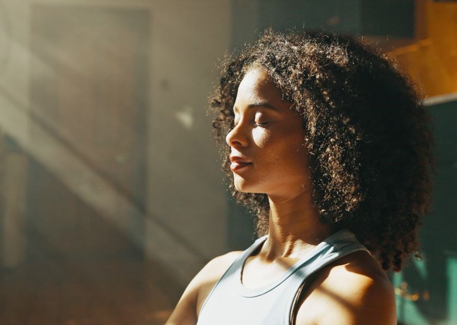 Kvinde nyder solstr�ler, der str�mmer ind gennem vinduet.