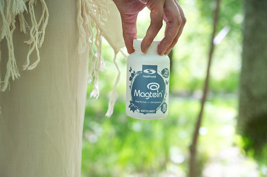 En h�nd holder en b�tte Magtein ude i en skov.