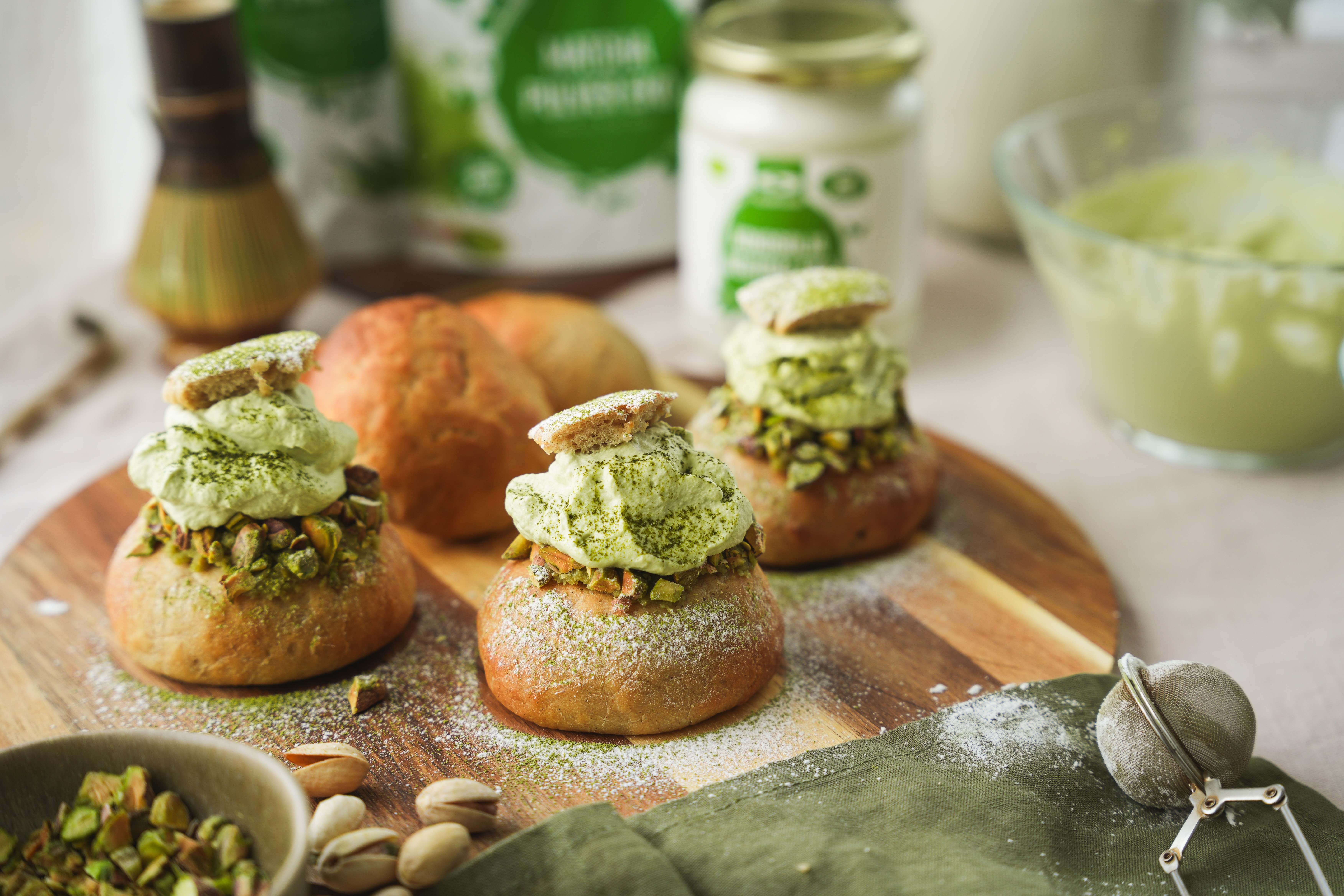 L�kre matcha-fastelavnsboller med smuk gr�n fl�de, anrettet p� et tr�fad.