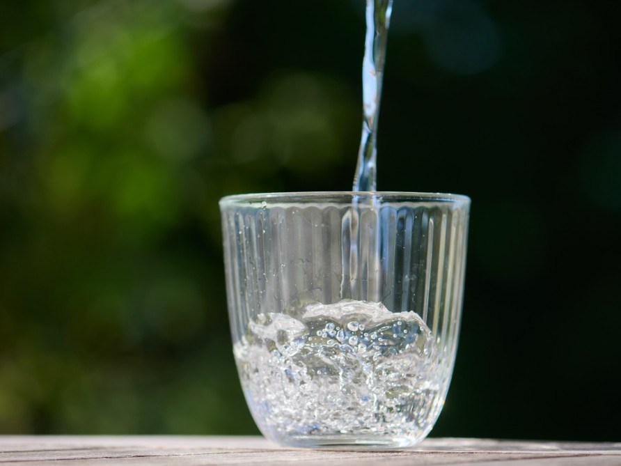 Et glas vand, der fyldes op mod en gr�n baggrund.