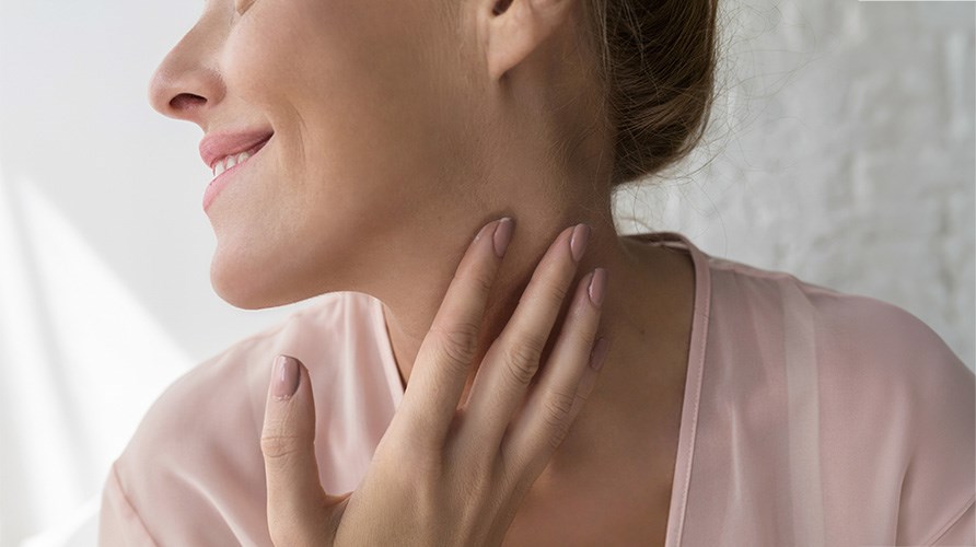 Kvinde i nærbillede som holder sin hånd over sin skjoldbruskkirtel. Kvinde i nærbillede som holder sin hånd over sin skjoldbruskkirtel.