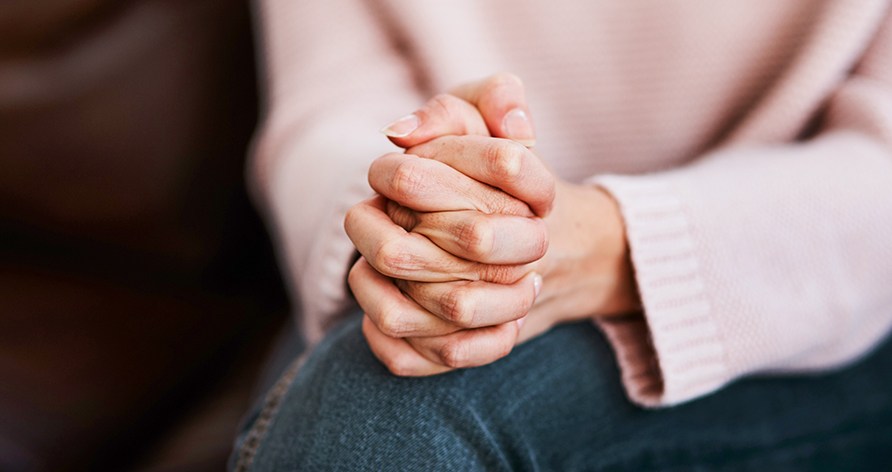 En kvinde holder sidder med hendes hænder samlet i sit skød. En kvinde holder sidder med hendes hænder samlet i sit skød.