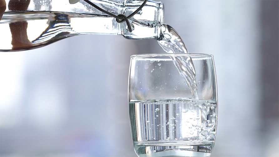Vand fra en glasflaske hldes op i et glas.