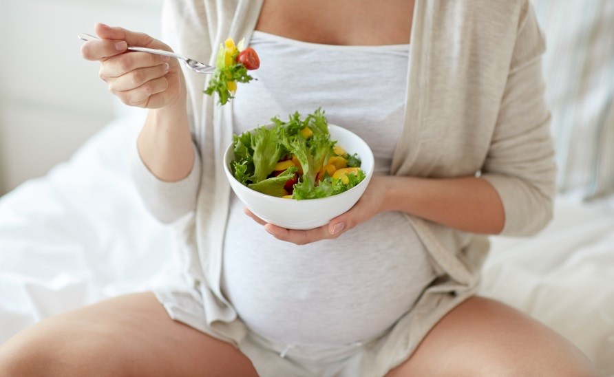 Gravid kvinde spiser salat.