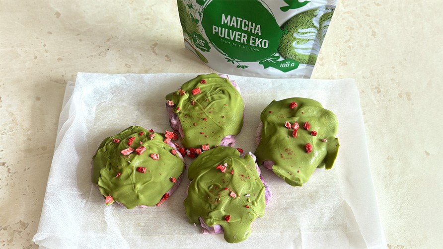 Frosne yoghurttoppe med bl�b�r og matcha p� en k�kkenbordplade sammen med en pose Healthwell Matcha Pulver �KO